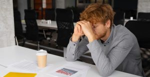 Massenentlassungen im Unternehmen, ein junger Angestellter stützt sich auf dem Tisch ab